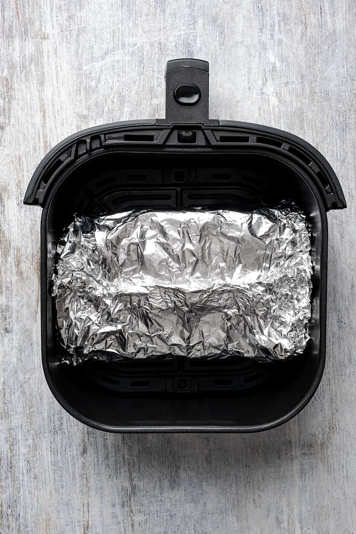 A foil-wrapped brisket in the air fryer.