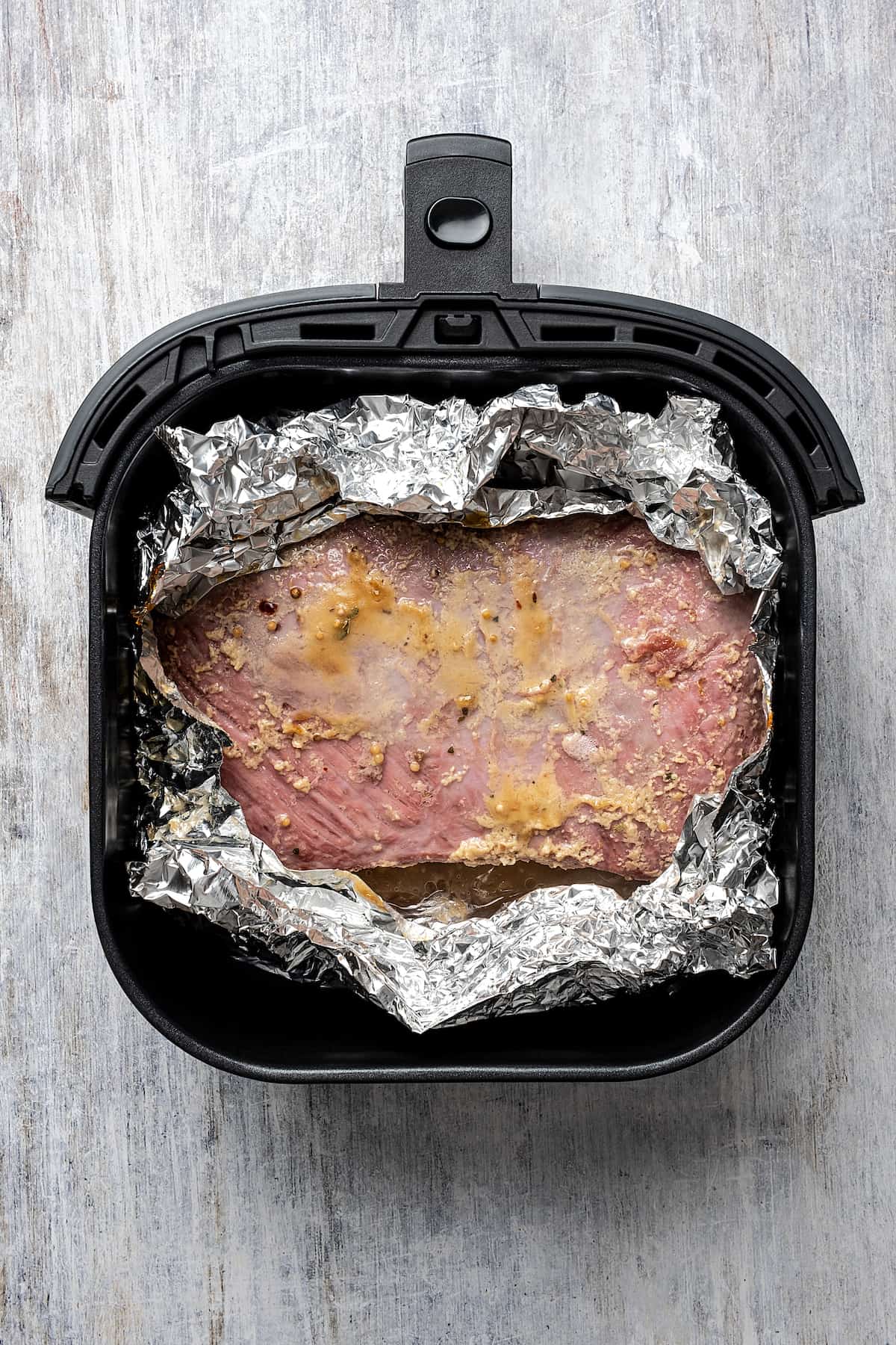 A brisket in a nest of foil in an air fryer.