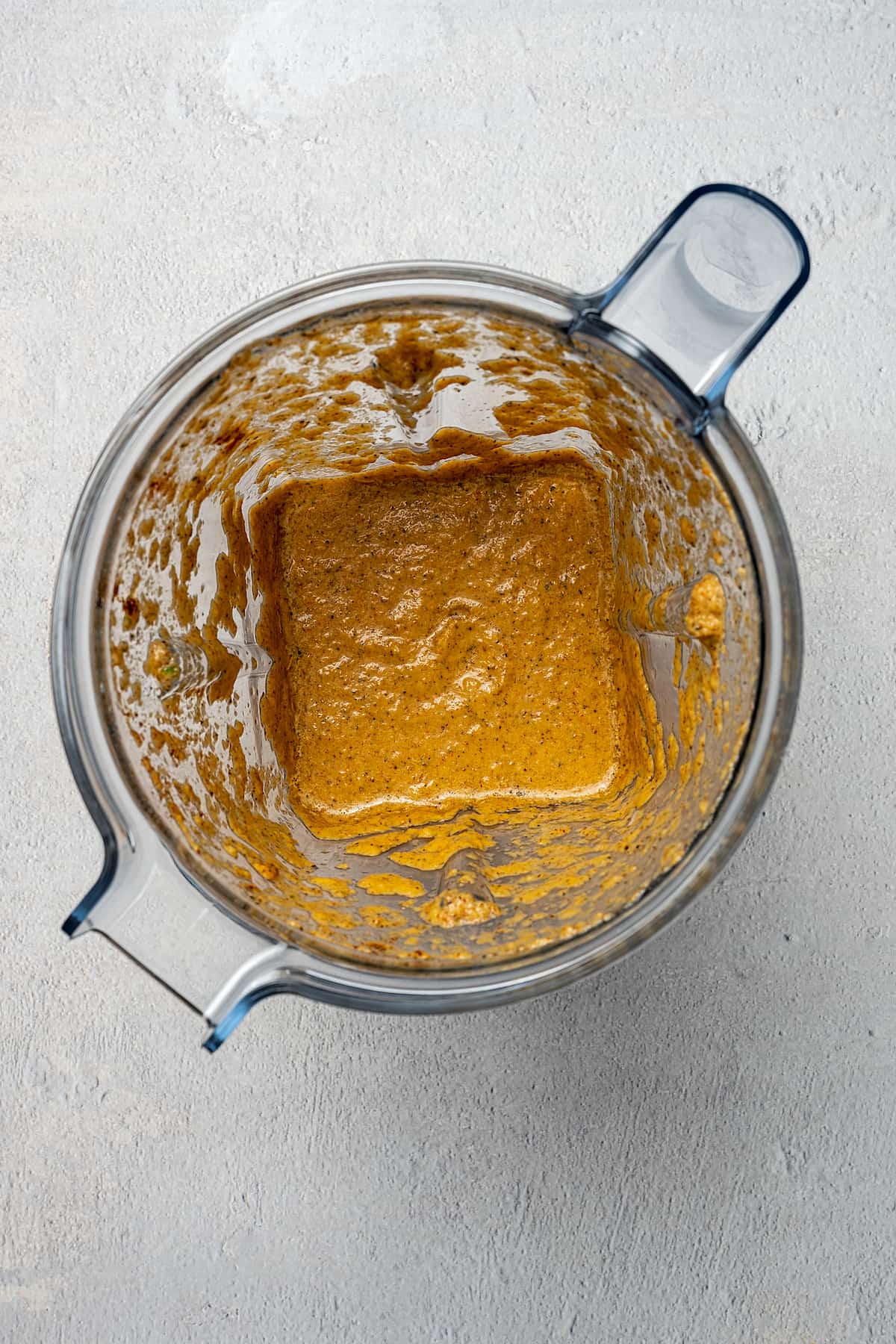 Overhead shot of a blender with pernil sauce in it.