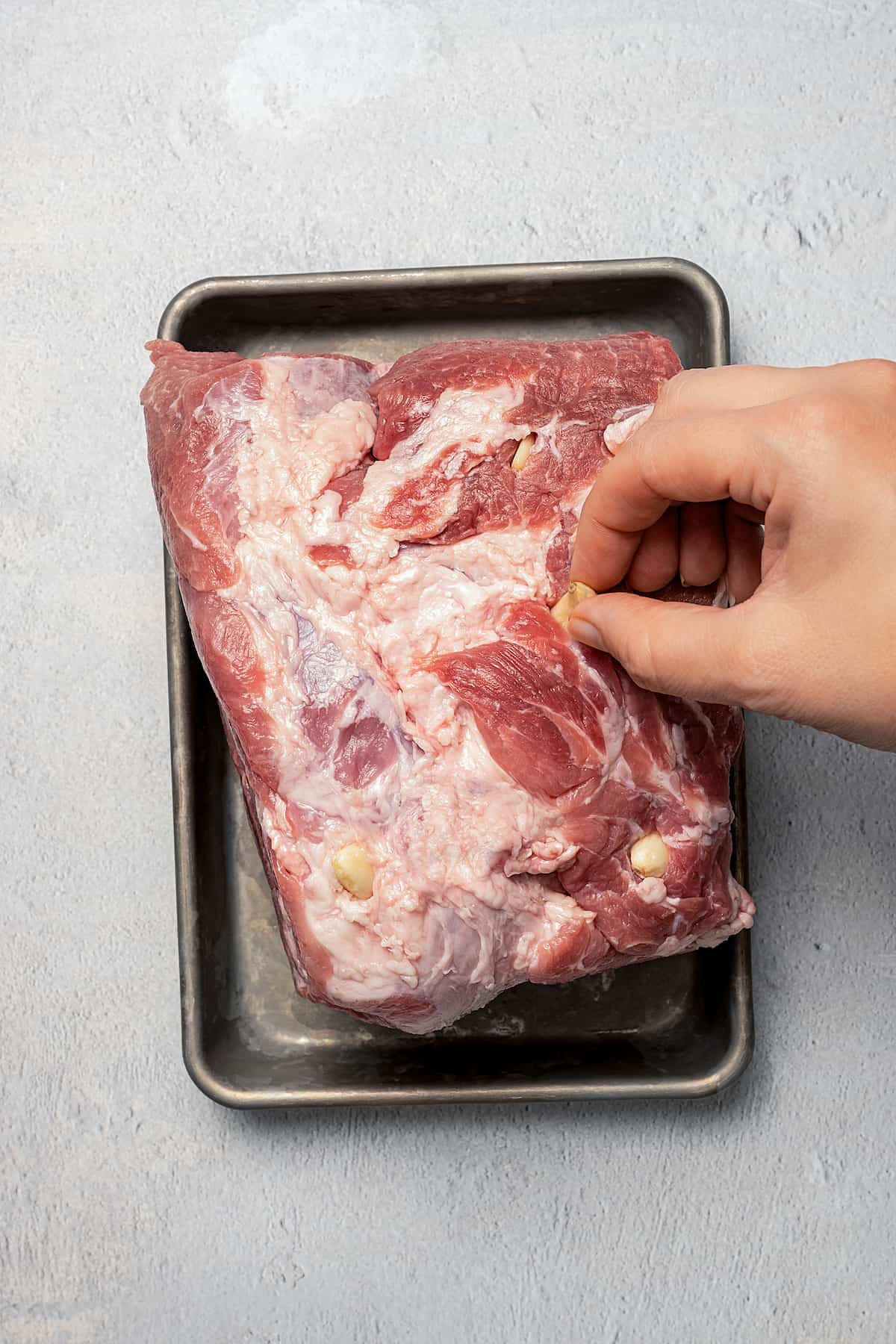 Inserting garlic cloves into a pork shoulder.