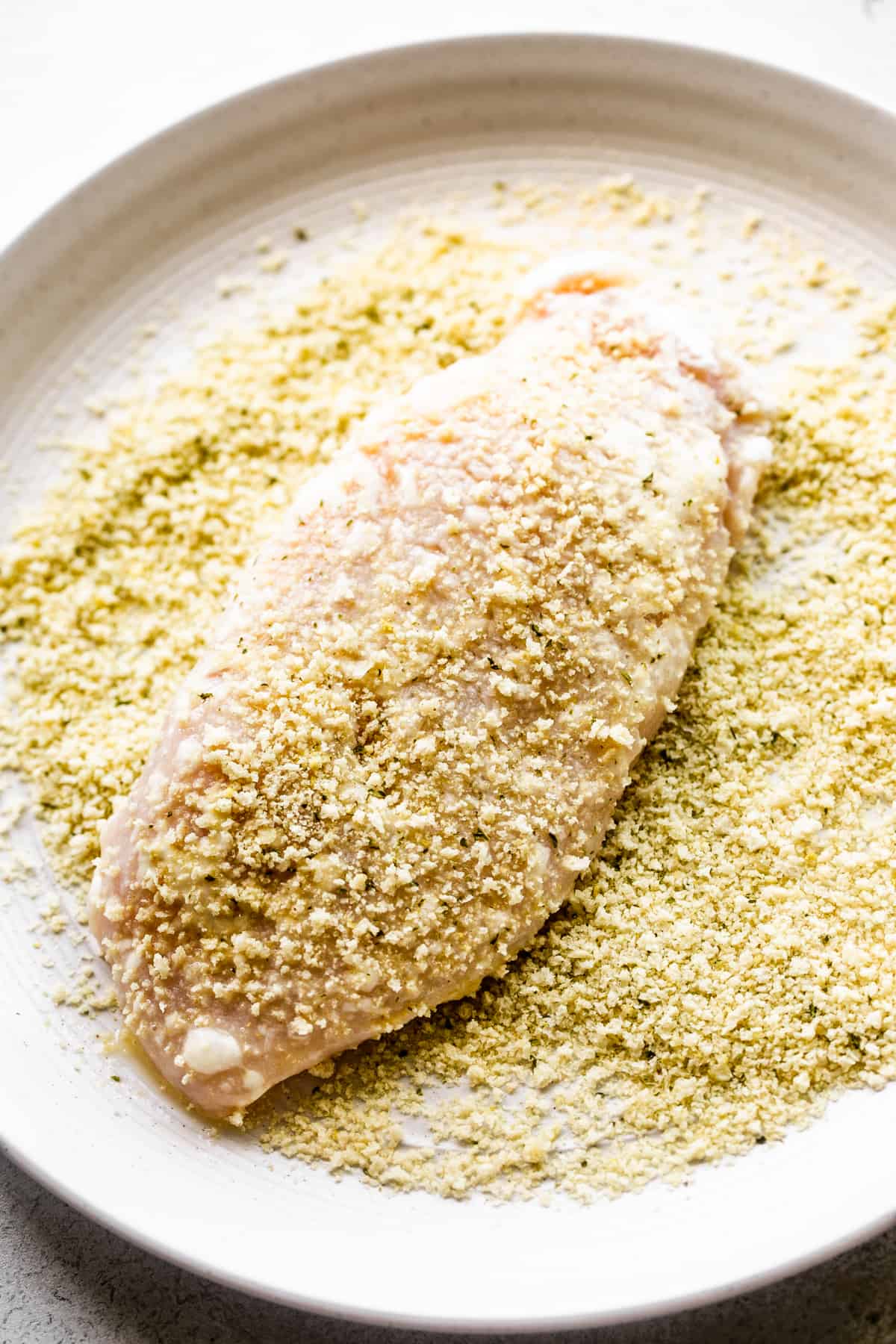 coating raw chicken breast with breading