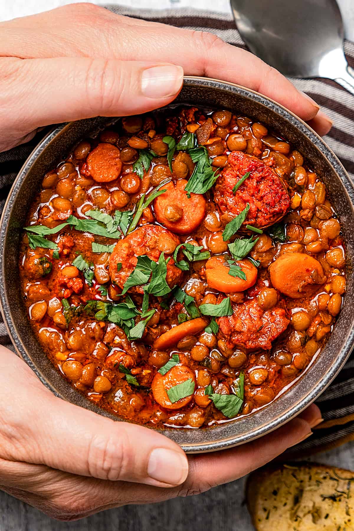 Two hands holding a bowl of lentil soup.