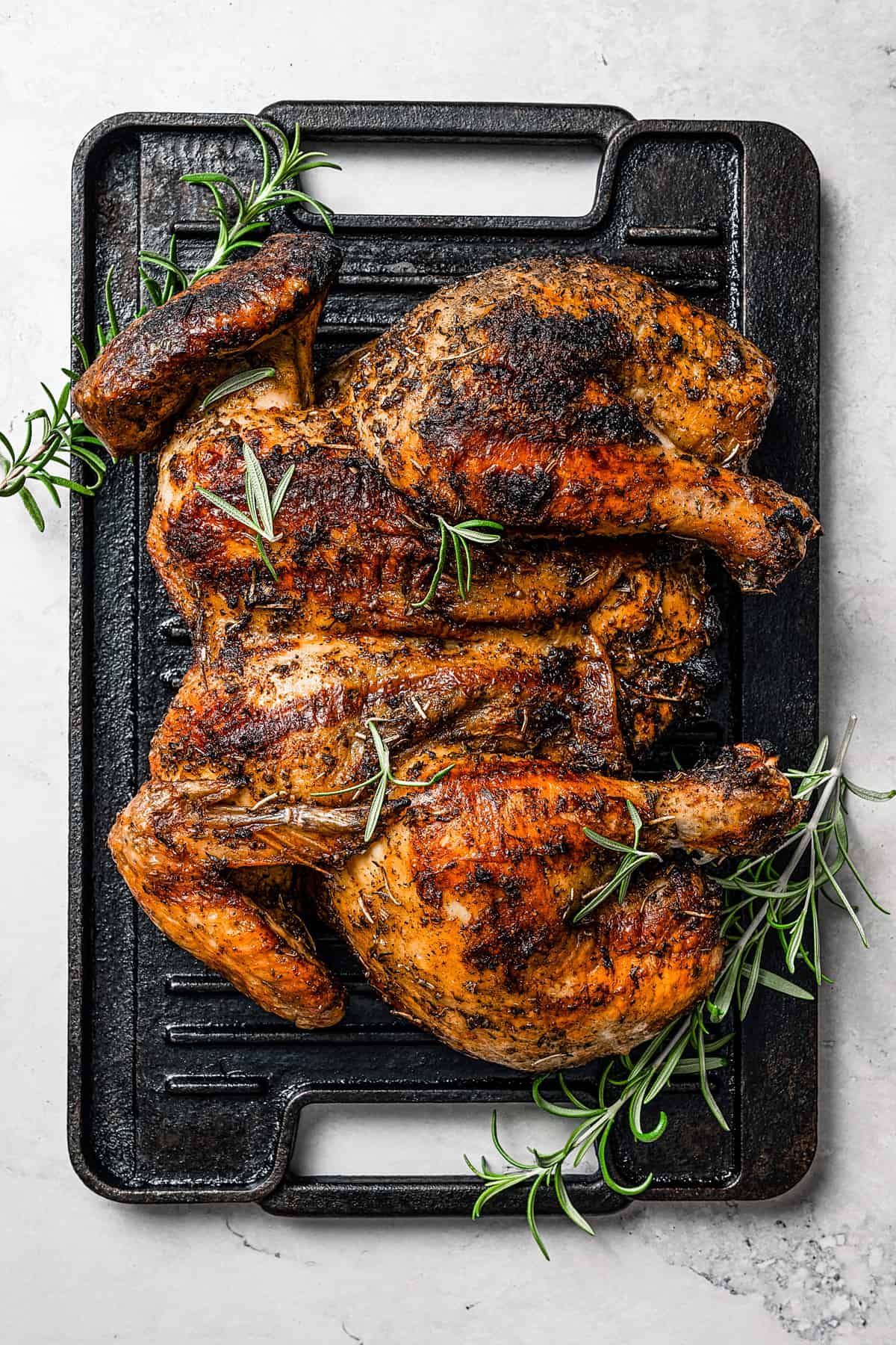 A spatchcocked whole chicken on a grill.