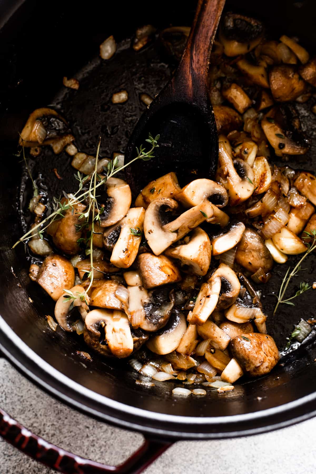 sauteeing chopped mushrooms in a dark dutch oven.