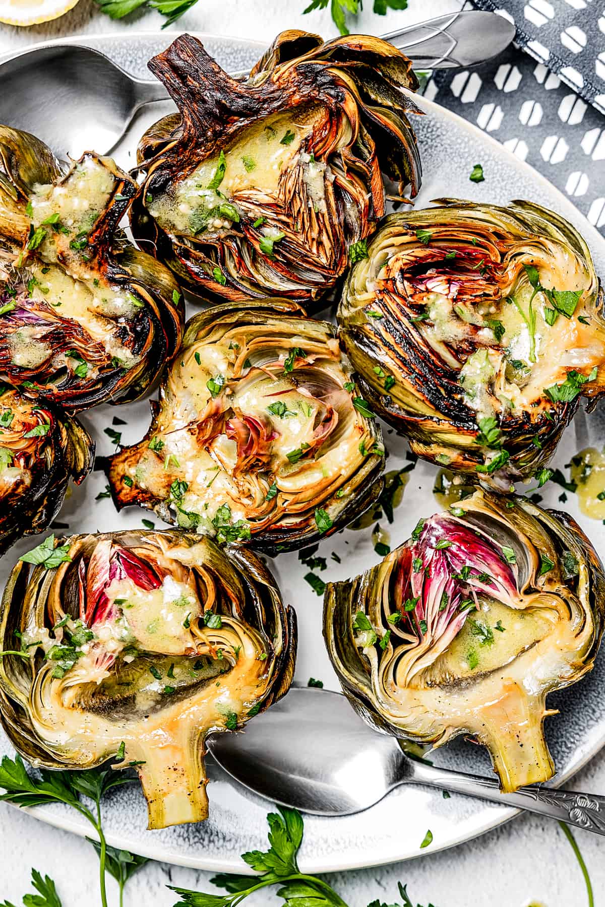 overhead shot of a serving plate with baked artichokes drizzled with lemon dressing.