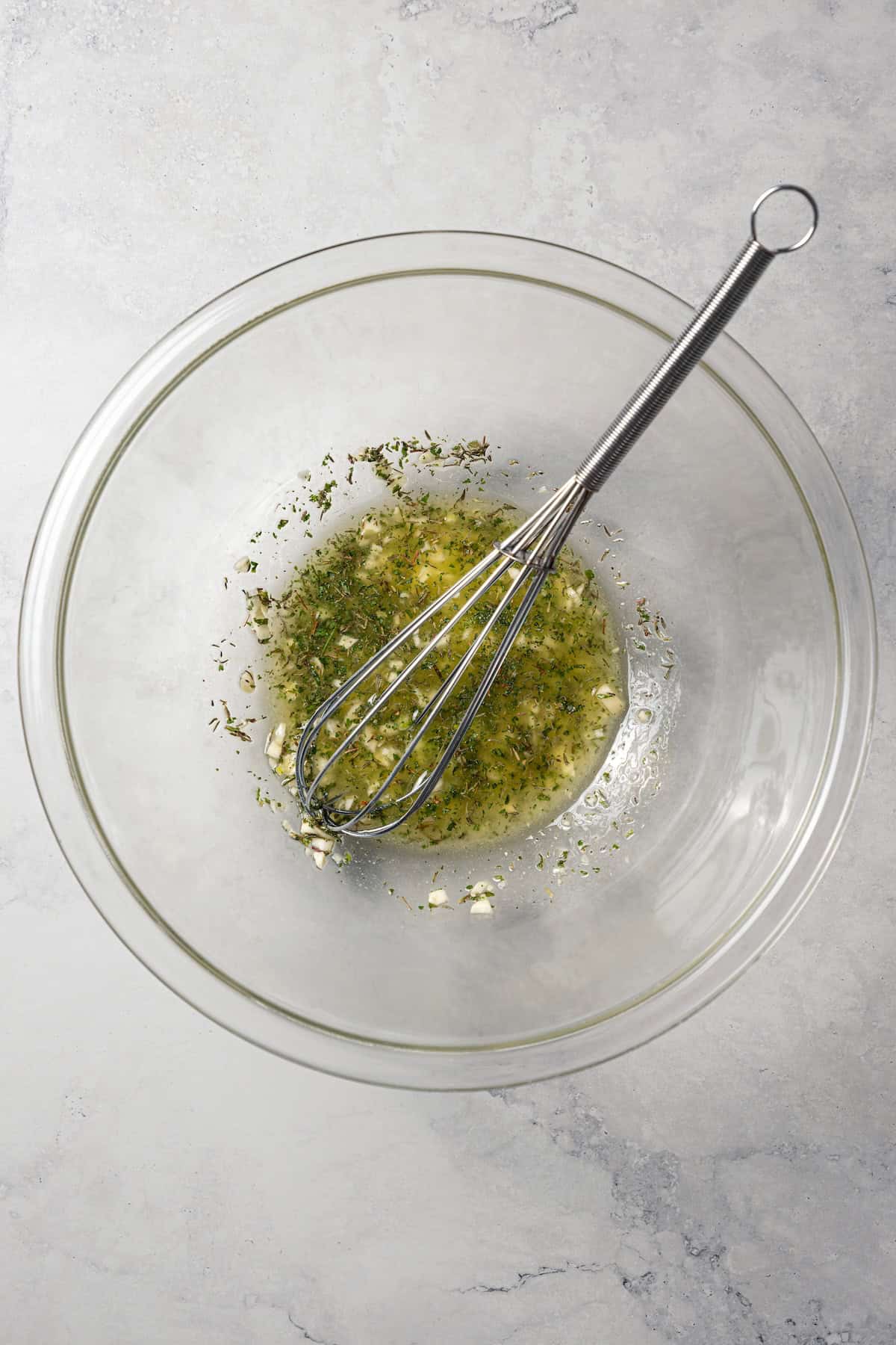 This roasted mushroom recipe combines buttery cremini mushrooms with garlic and herbs. It's a quick, easy side dish with only 5 ingredients! Melted garlic and herb butter in a bowl with a whisk.