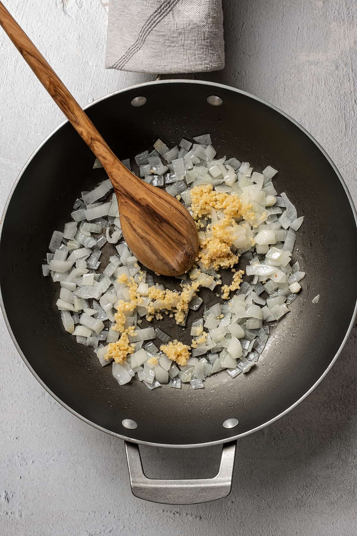 Stirring garlic into a skillet of onions.