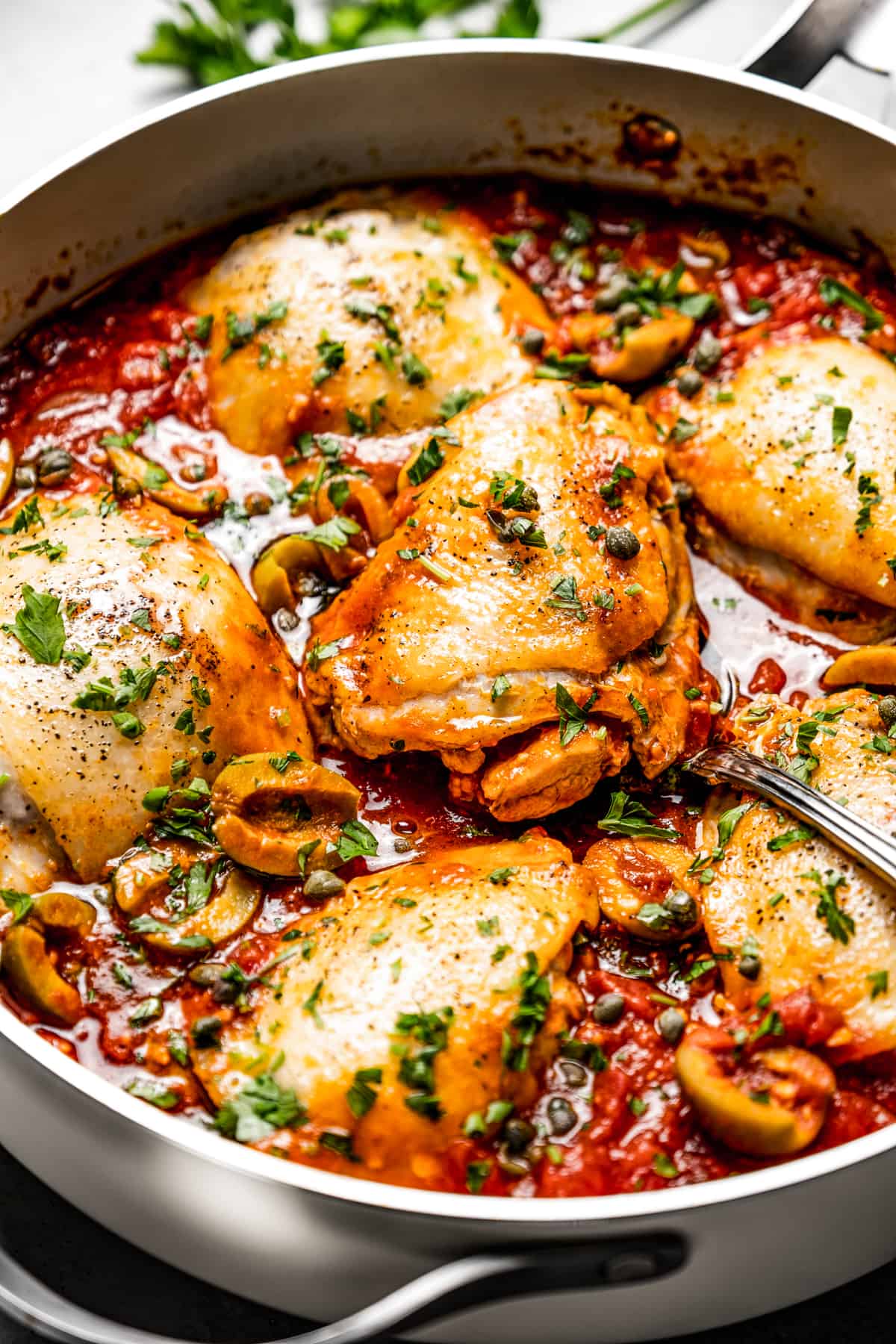A deep-sided skillet with chickens in a homemade red sauce.