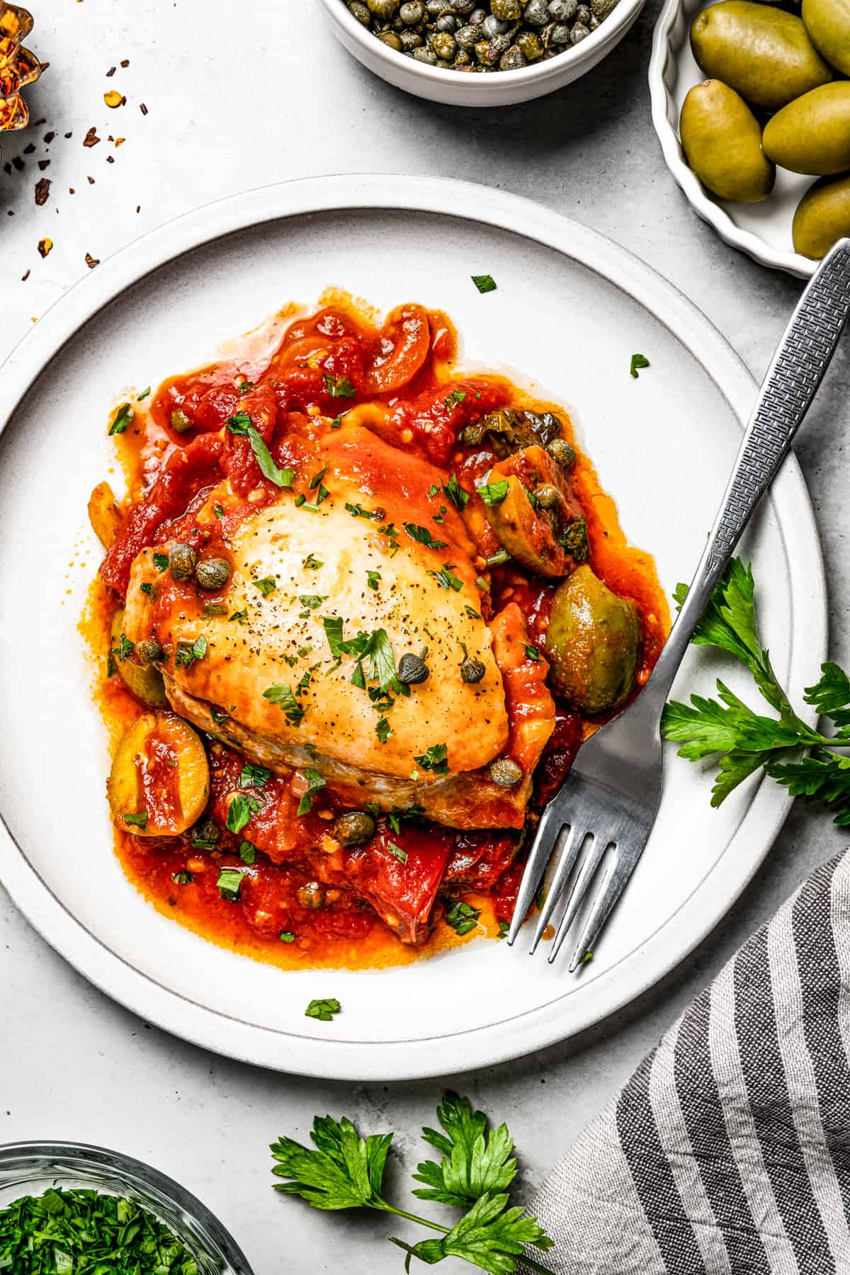 A serving of homemade sauce and bone-in chicken thighs, garnished with herbs.