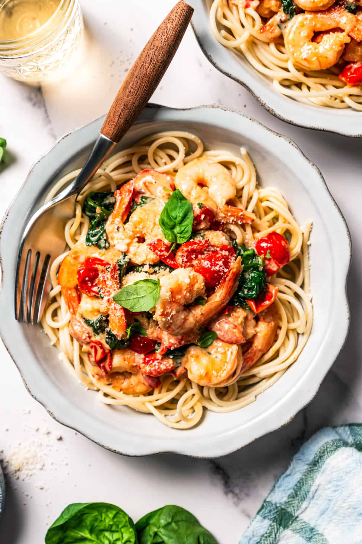 A bowl of spaghetti topped with Tuscan shrimp.