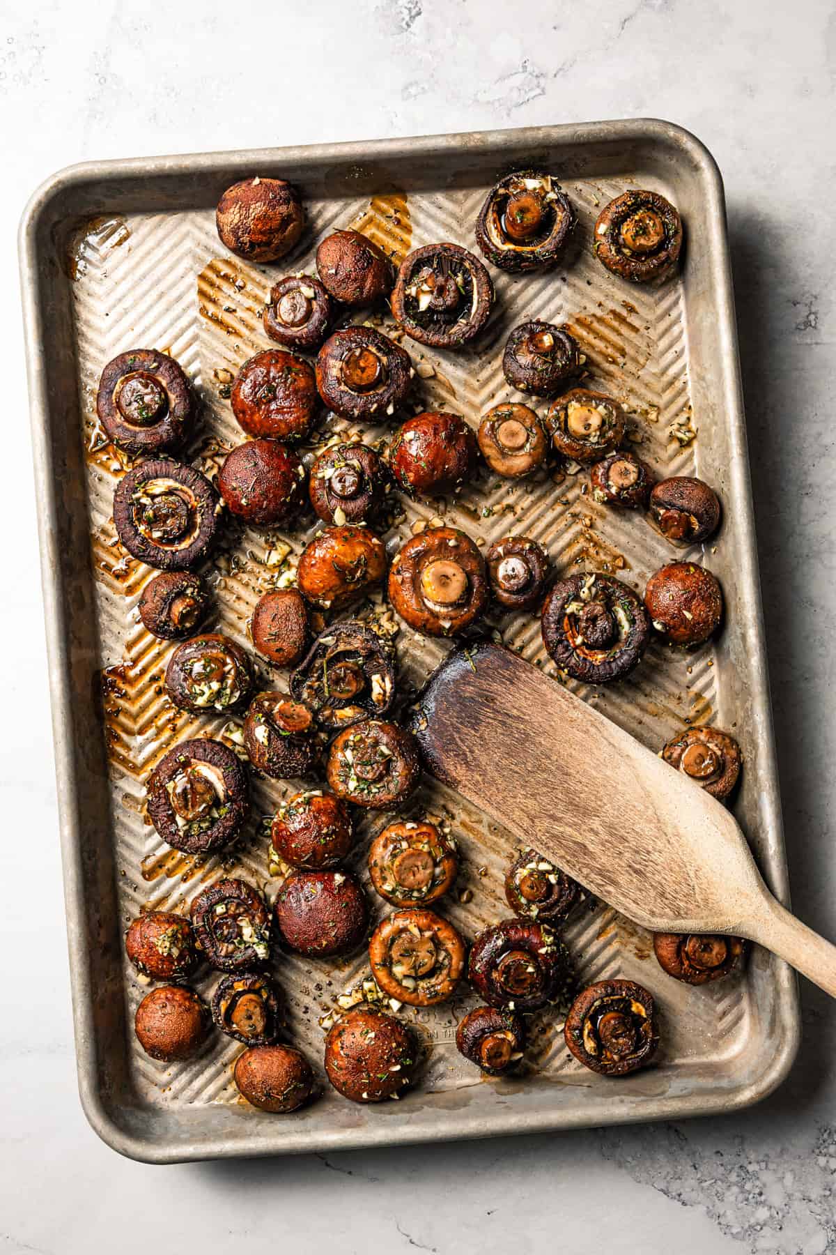 This roasted mushroom recipe combines buttery cremini mushrooms with garlic and herbs. It's a quick, easy side dish with only 5 ingredients! Roasted mushrooms on a baking sheet.