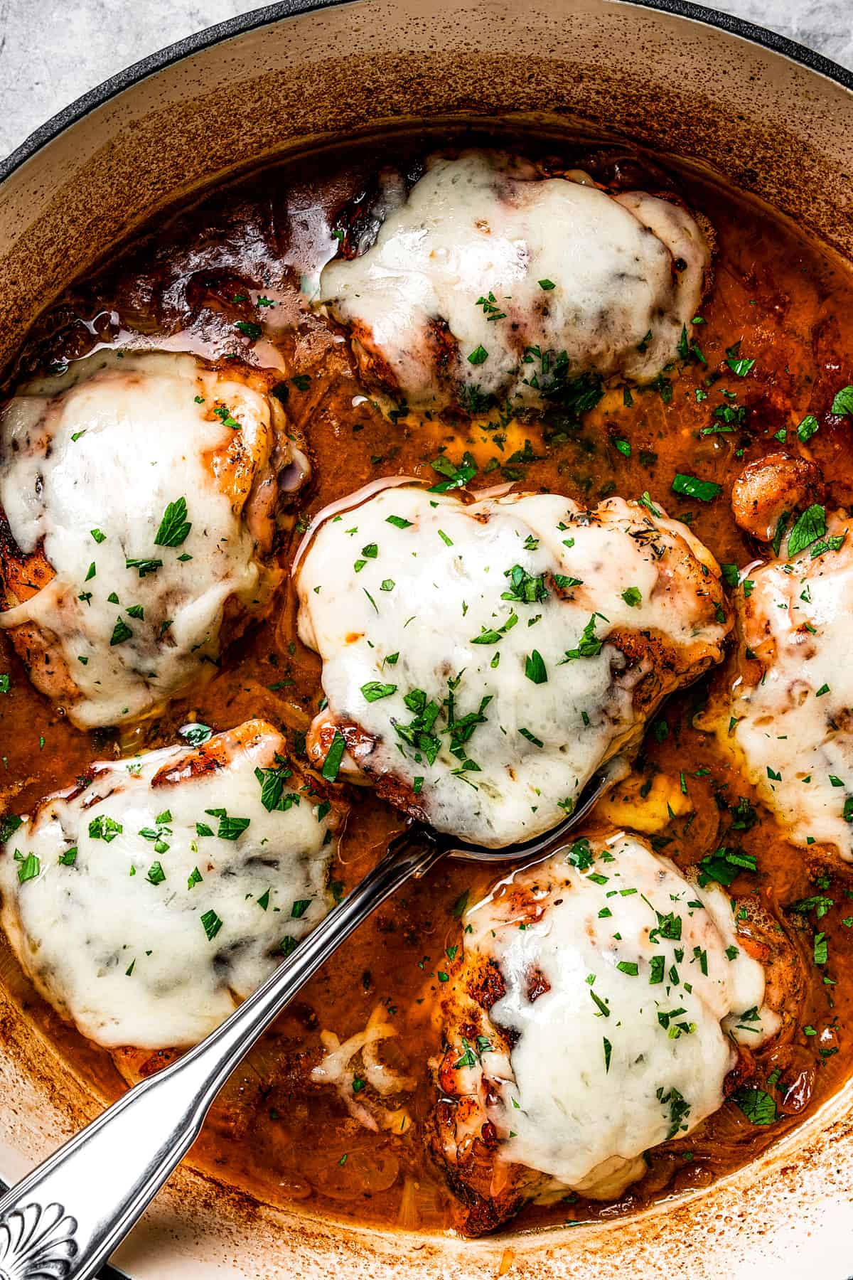 A pan of cheesy chicken thighs in French onion sauce.