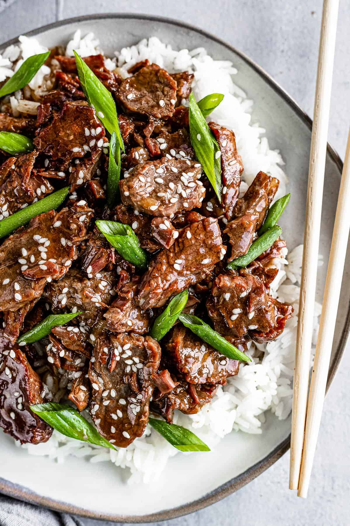 Instant Pot Mongolian Beef arranged on a plate over a bed of rice.