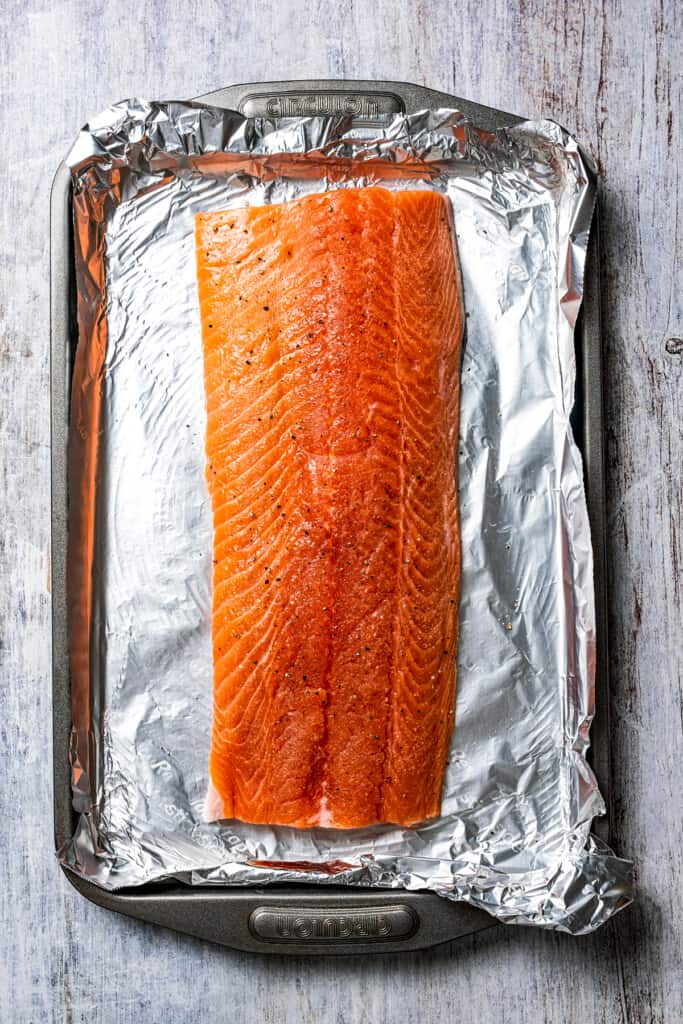 A fillet of salmon sprinkled with salt and pepper.