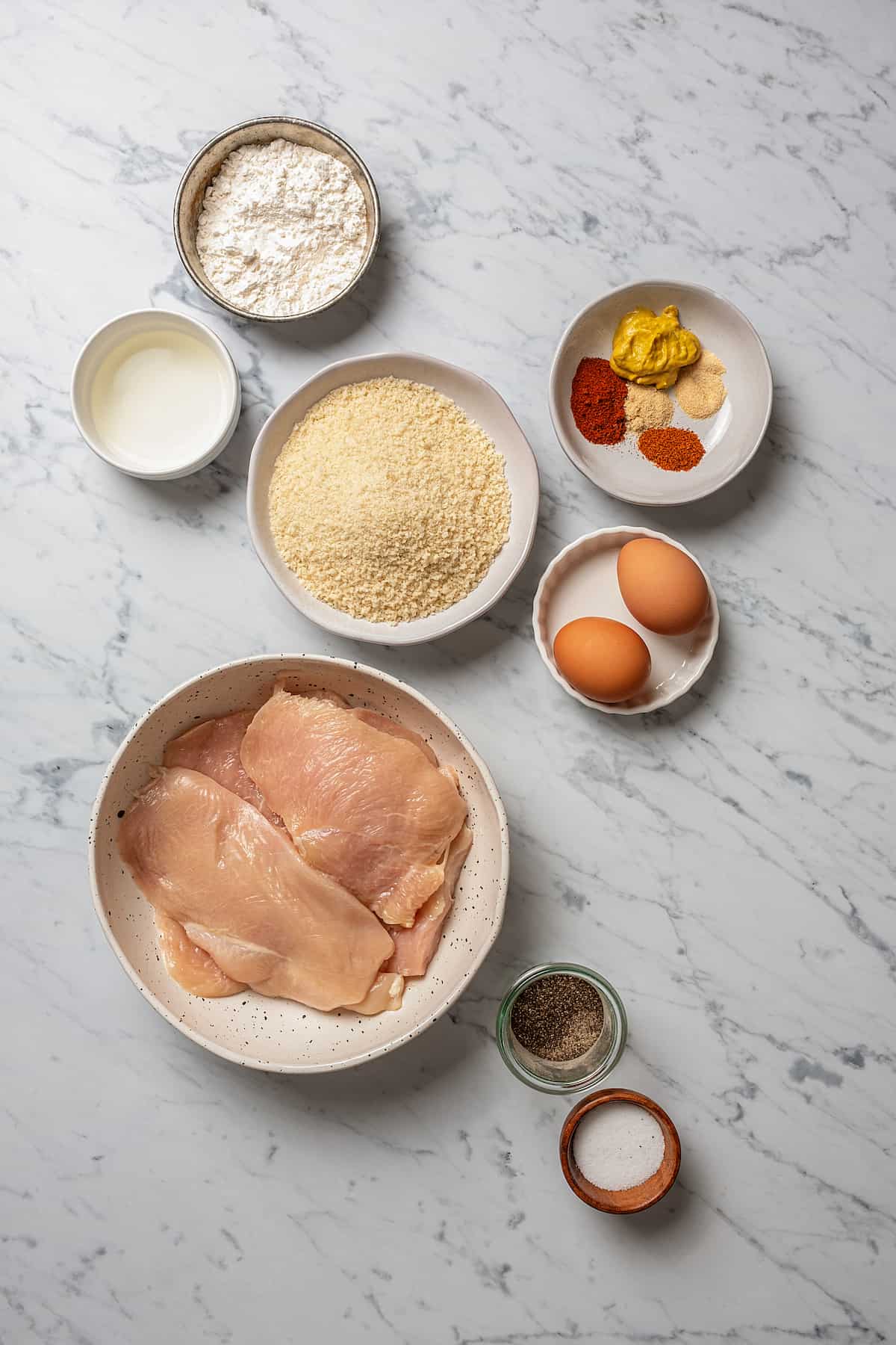 From top: flour, seasonings, oil, bread crumbs, eggs, chicken cutlets, salt, and pepper.
