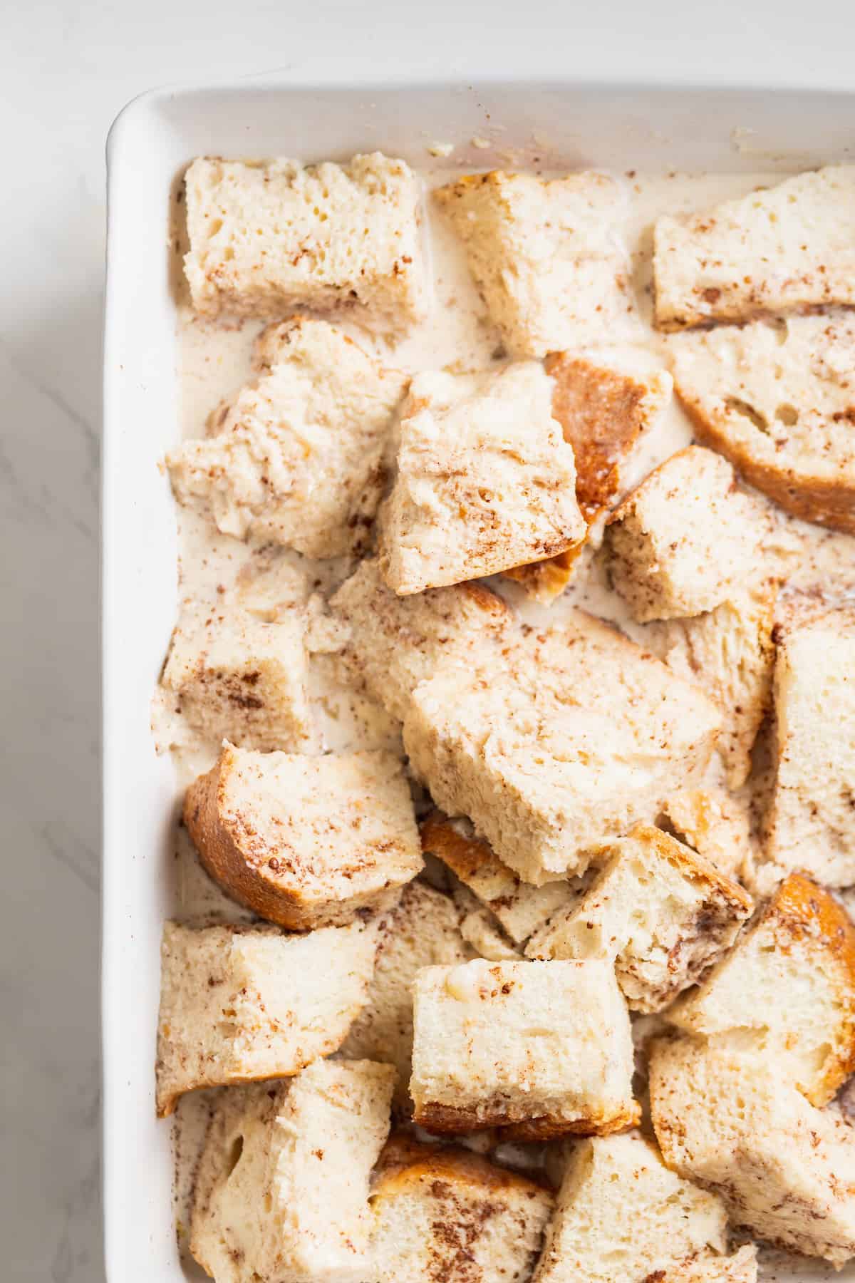 Placing the diced bread in the baking dish.