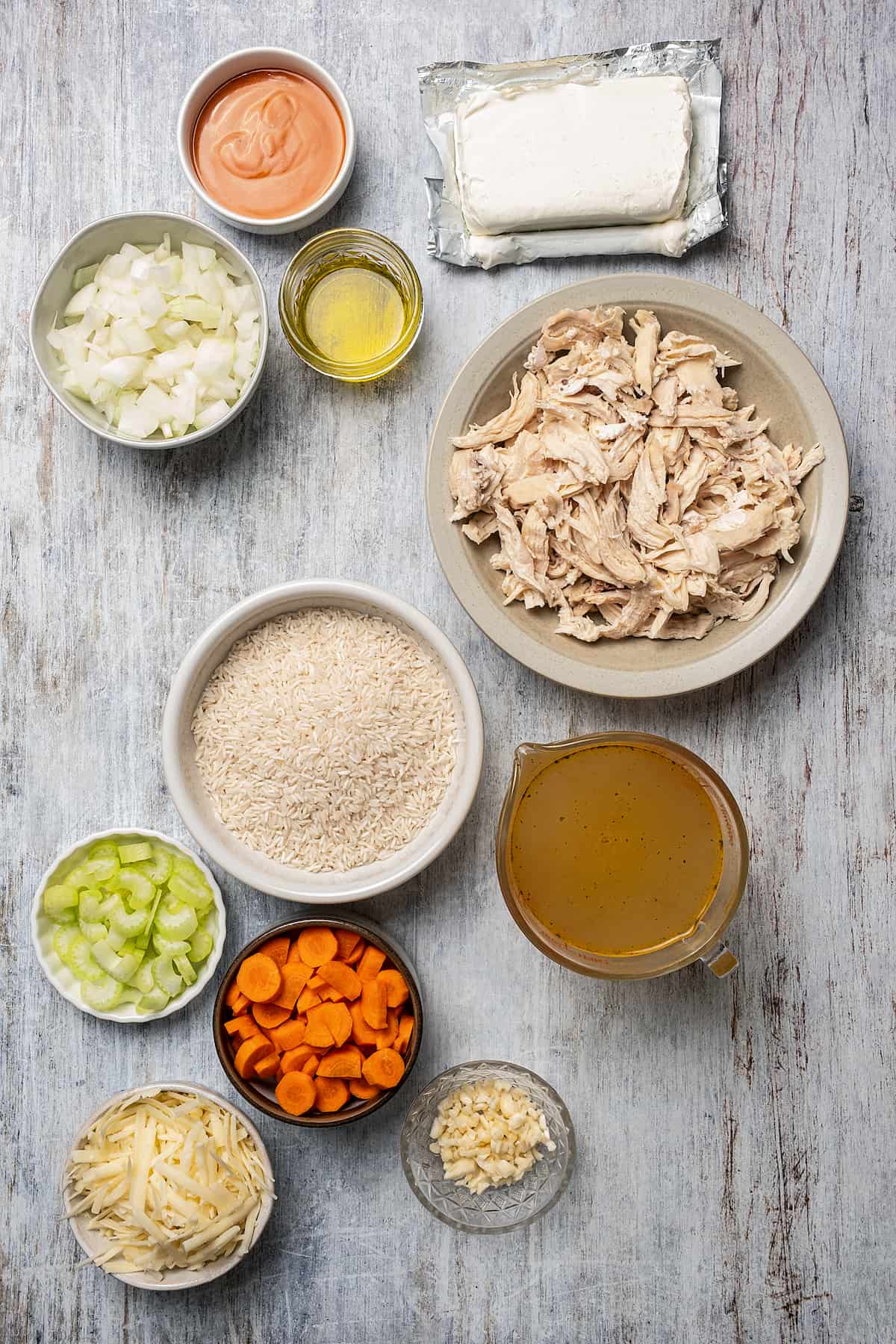 From top: Buffalo sauce, oil, cream cheese, diced onion, shredded chicken, rice, broth, celery, carrots, white cheddar, garlic.