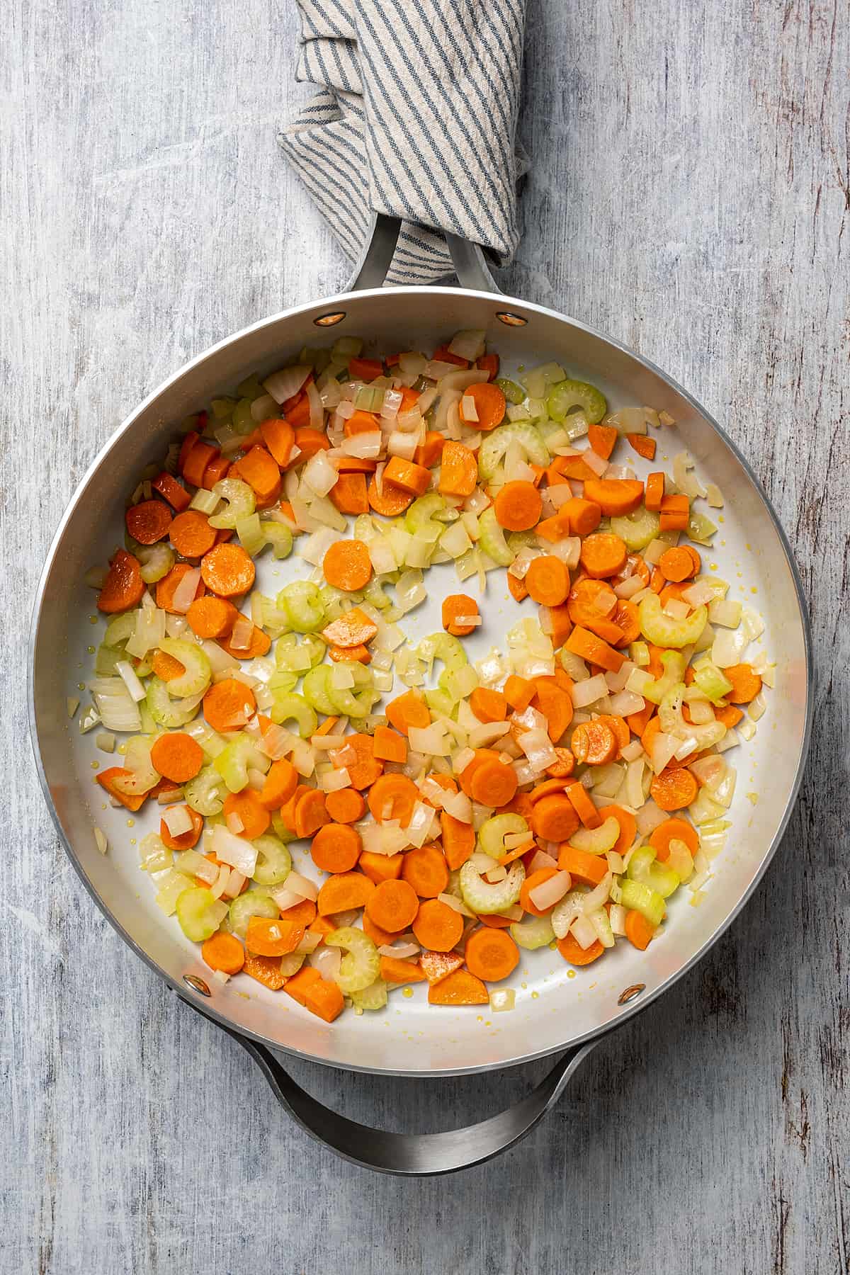 Carrots, onions, and celery cooking in a large skillet.