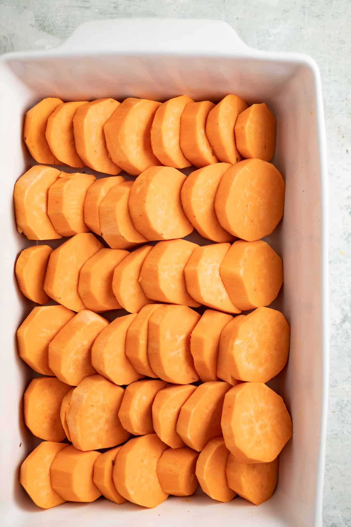 Arranging the sweet potatoes in the baking dish.