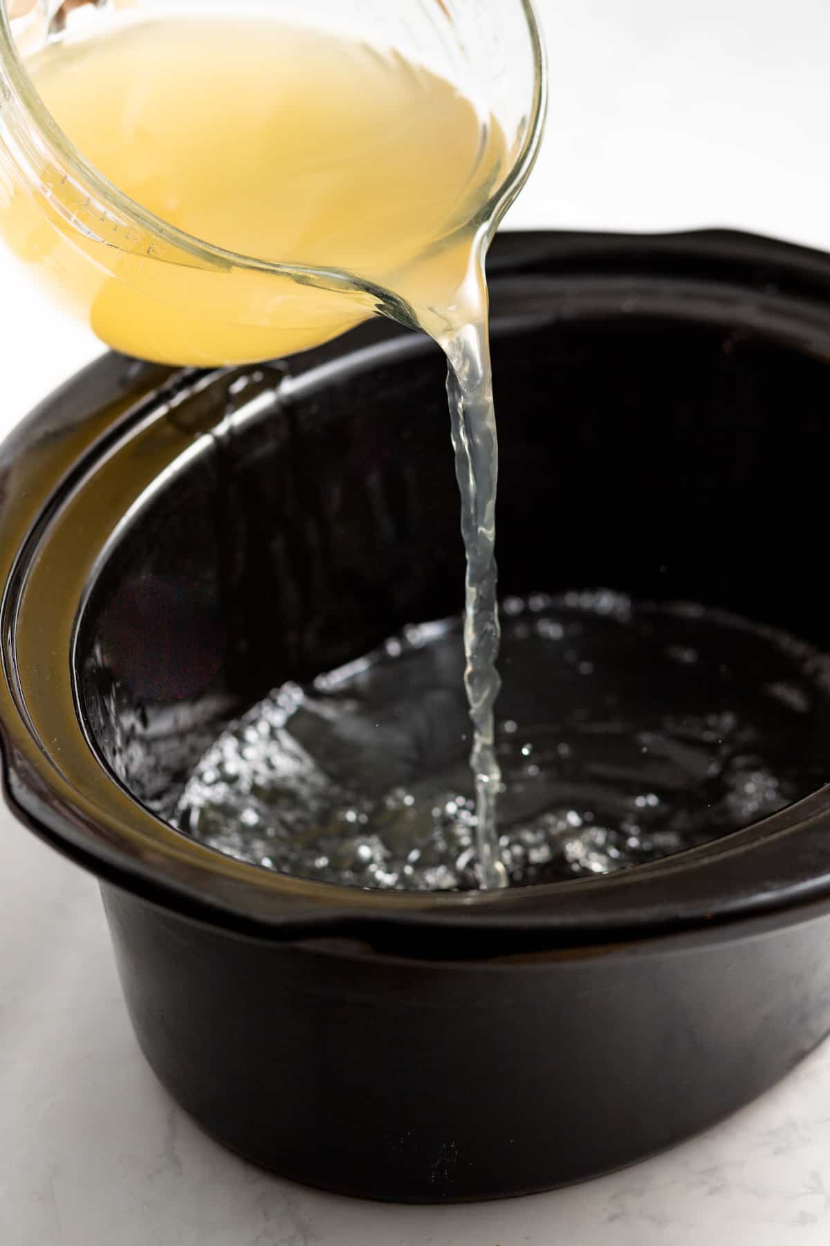 Pouring the broth into the crockpot.