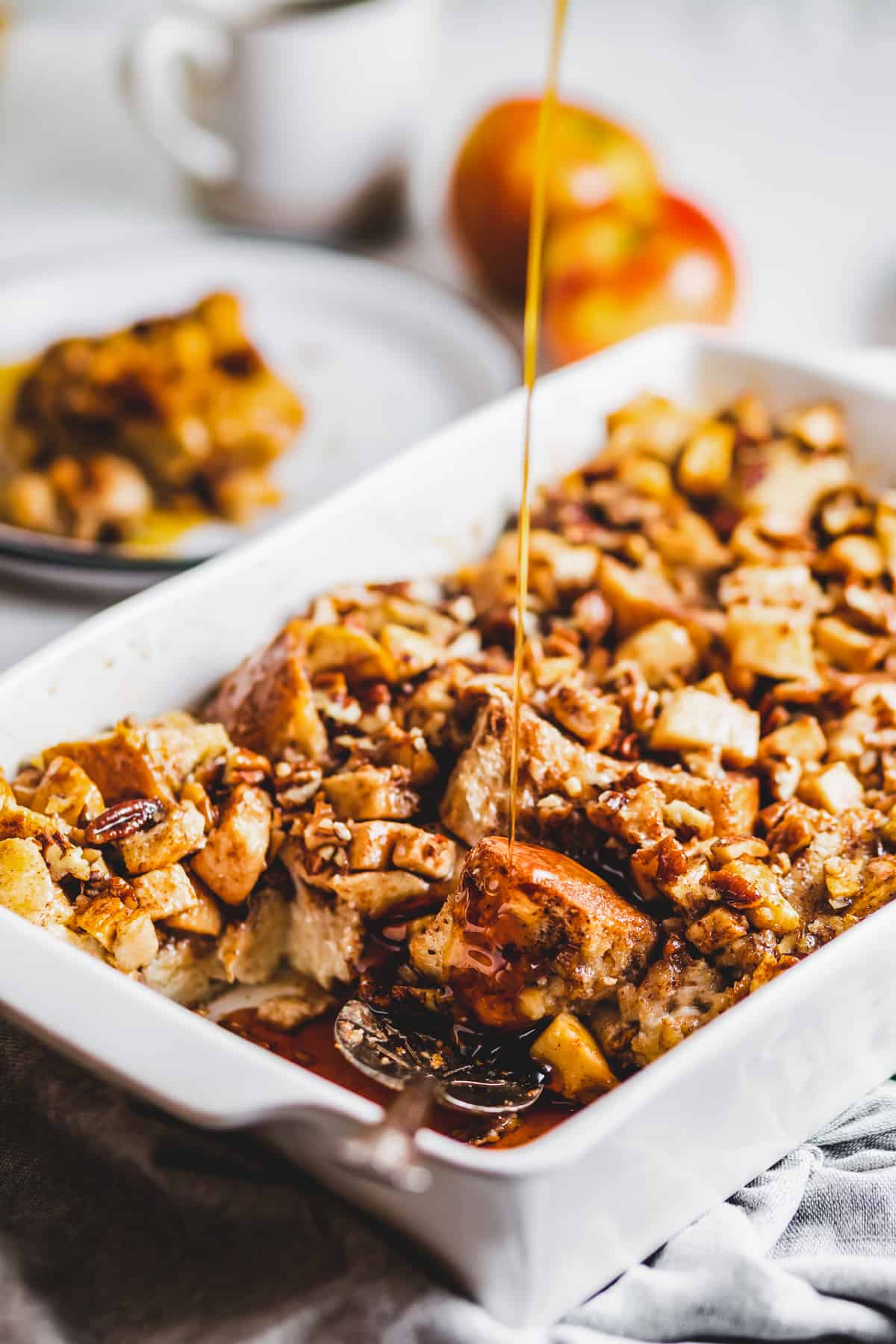 pouring syrup over apple french toast casserole.