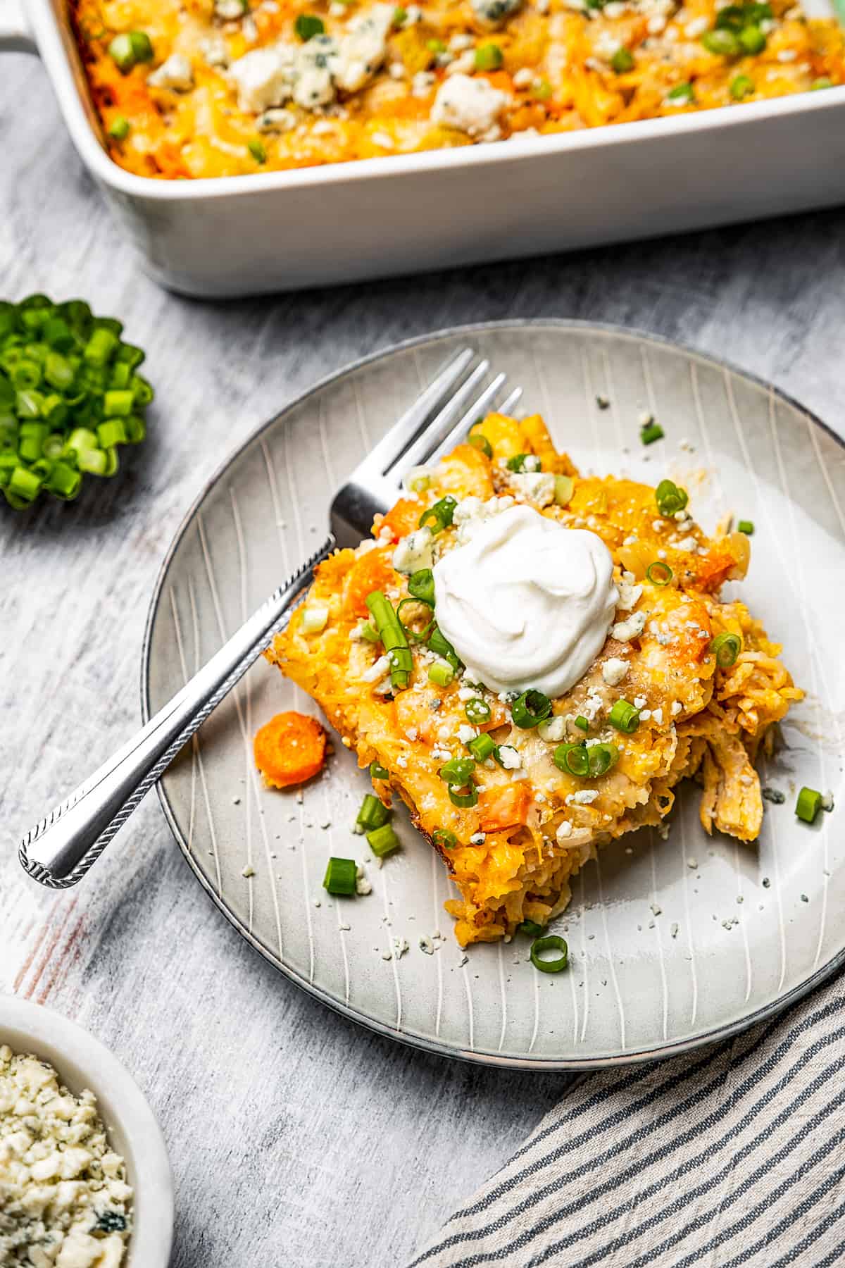 A square piece of buffalo chicken and rice casserole topped with a dollop of sour cream.
