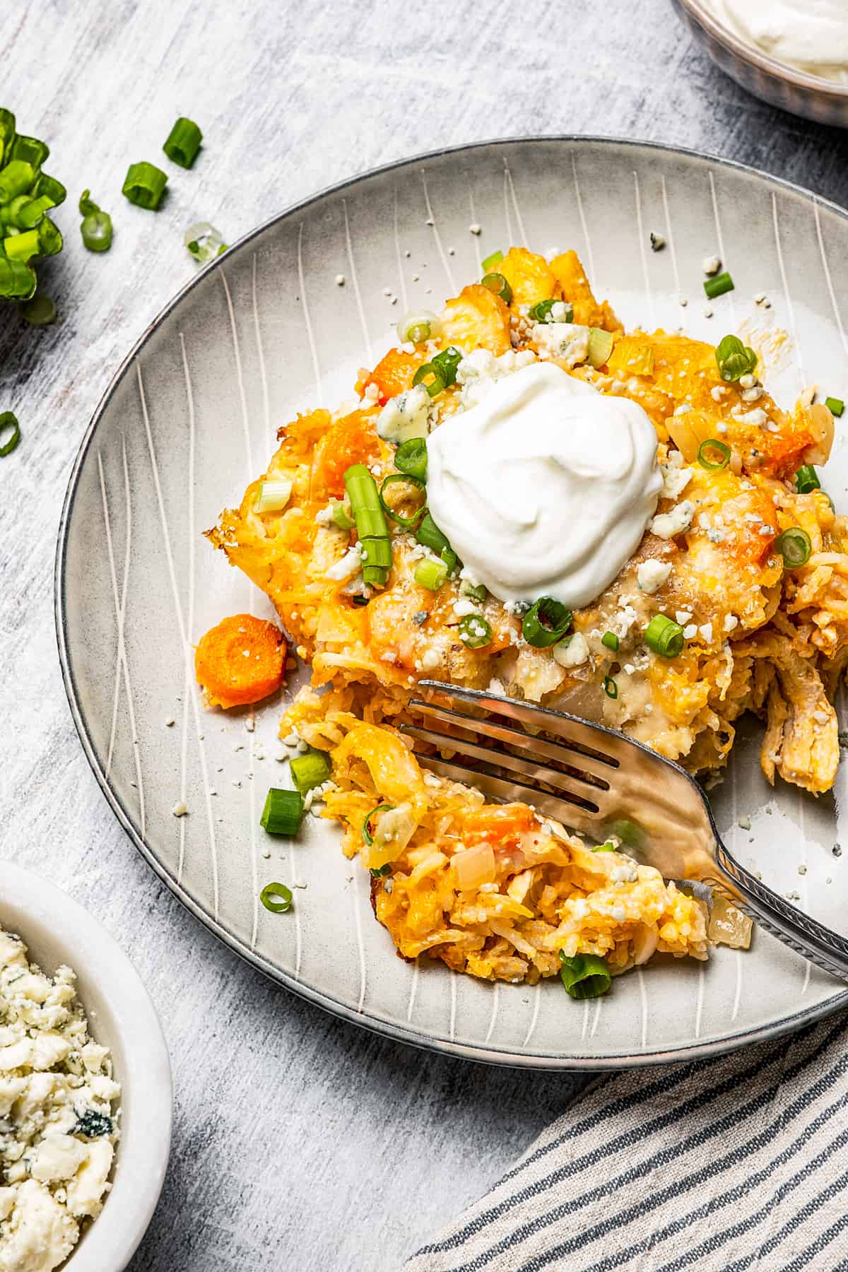 Cutting a bite from a square of buffalo chicken and rice casserole with a fork.