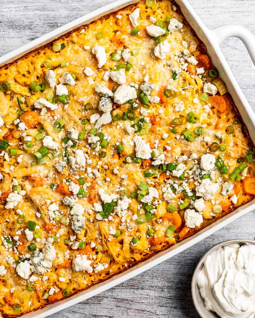 White baking dish with a buffalo-style chicken casserole with rice and toppings.