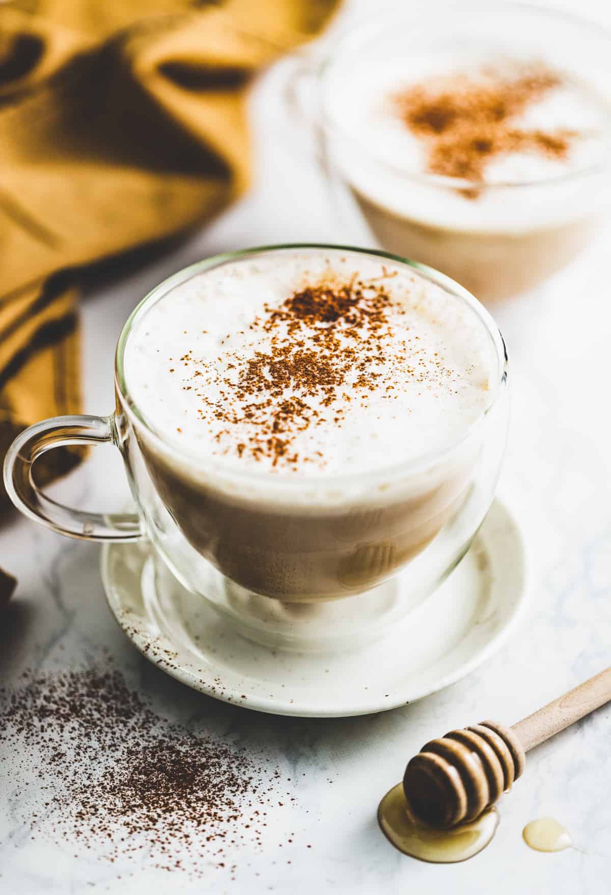 Dirty chai latte topped with cinnamon in a crystal coffee mug.
