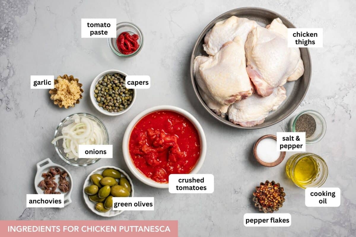Chicken Puttanesca an easy dinner, made with juicy chicken thighs in a zesty tomato-based sauce with garlic, olives, capers, and more. Chicken puttanesca ingredients with text labels placed over each ingredient.