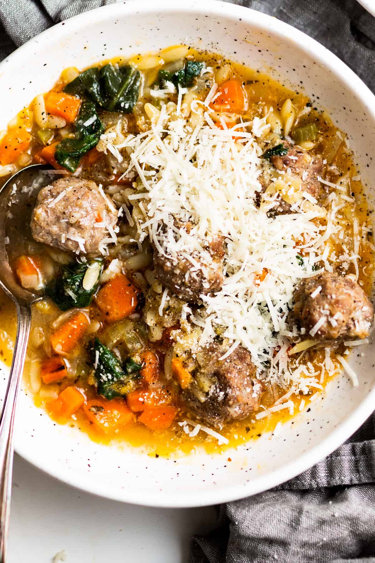 Close-up of Italian wedding soup in a bowl, garnished with shredded parmesan.