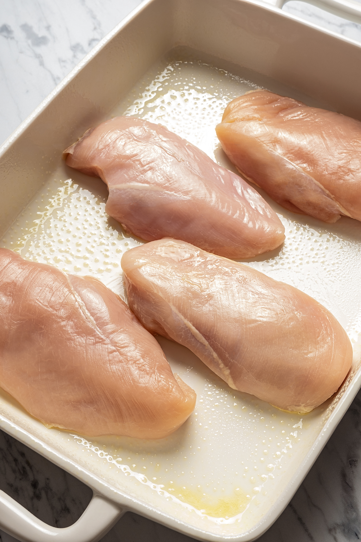 Uncooked chicken breasts in baking dish