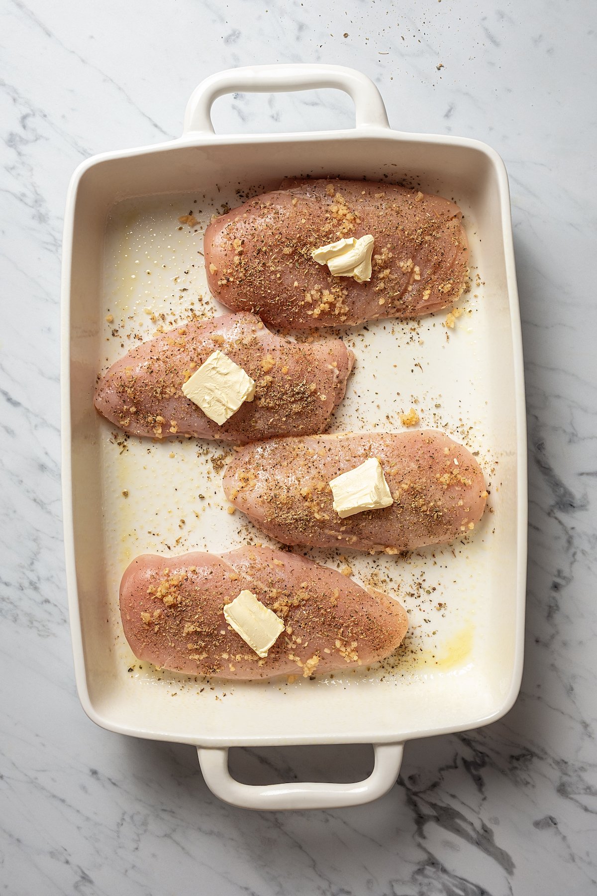 4 chicken breasts in baking dish, each topped with pat of butter
