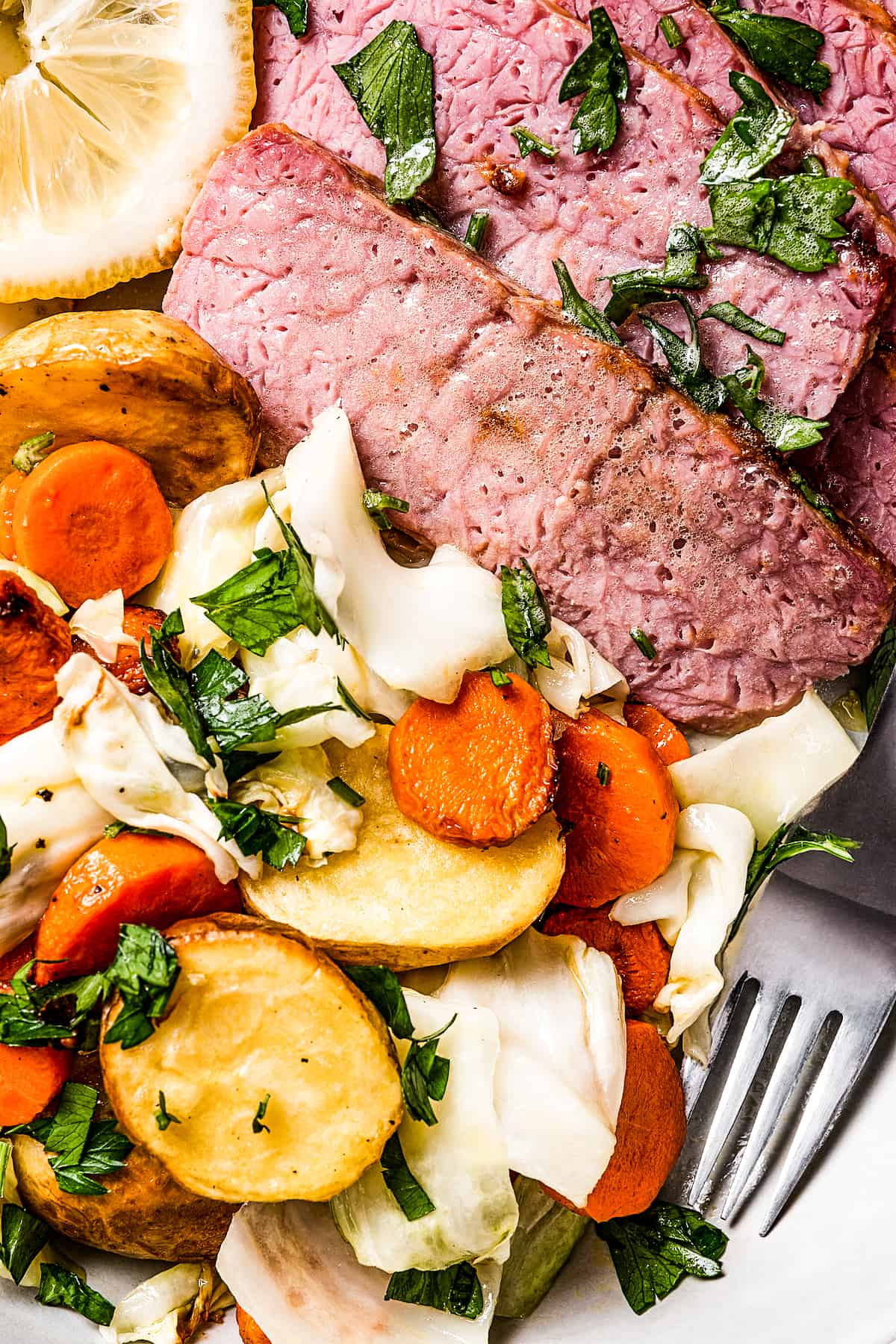 Corned beef slices next to a medley of vegetables.
