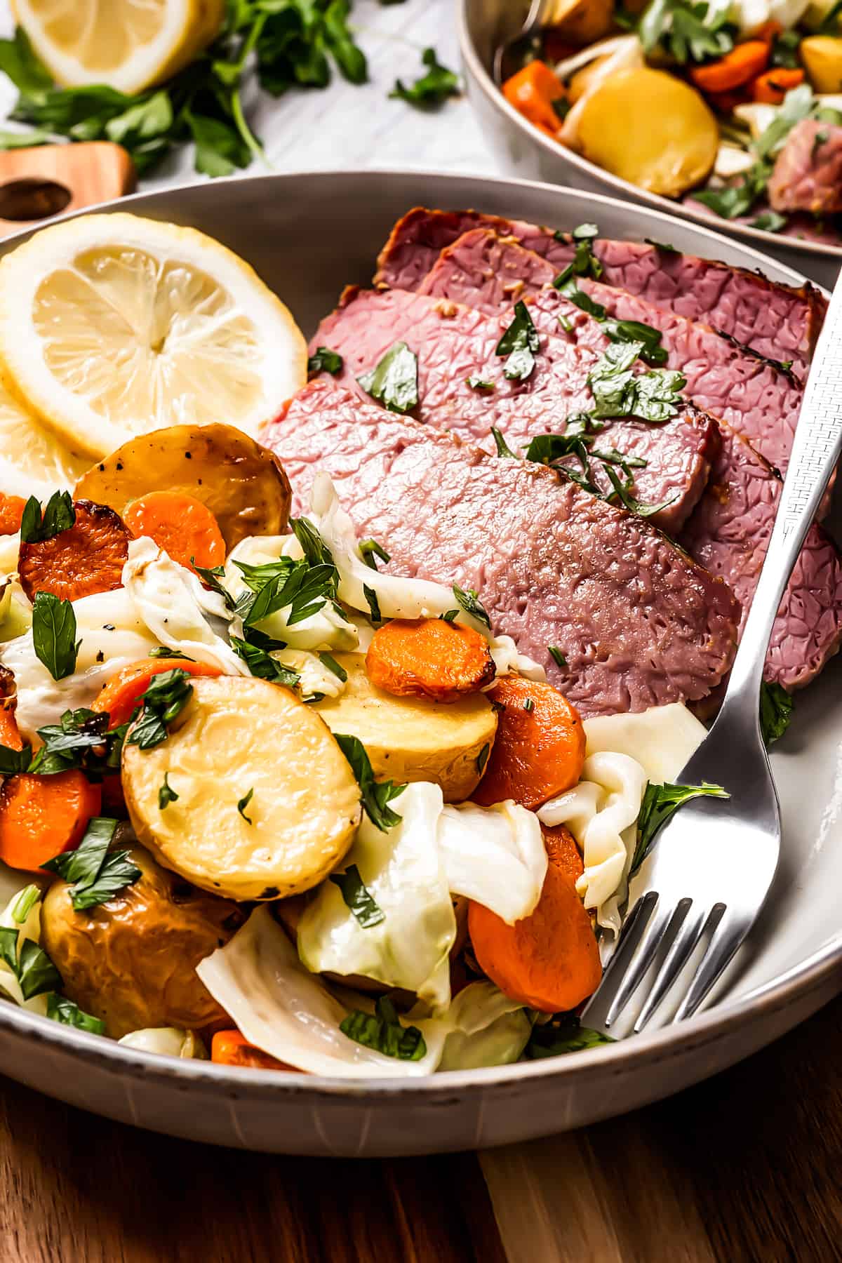 A plate with sliced beef, mixed vegetables, and fresh lemon slices.