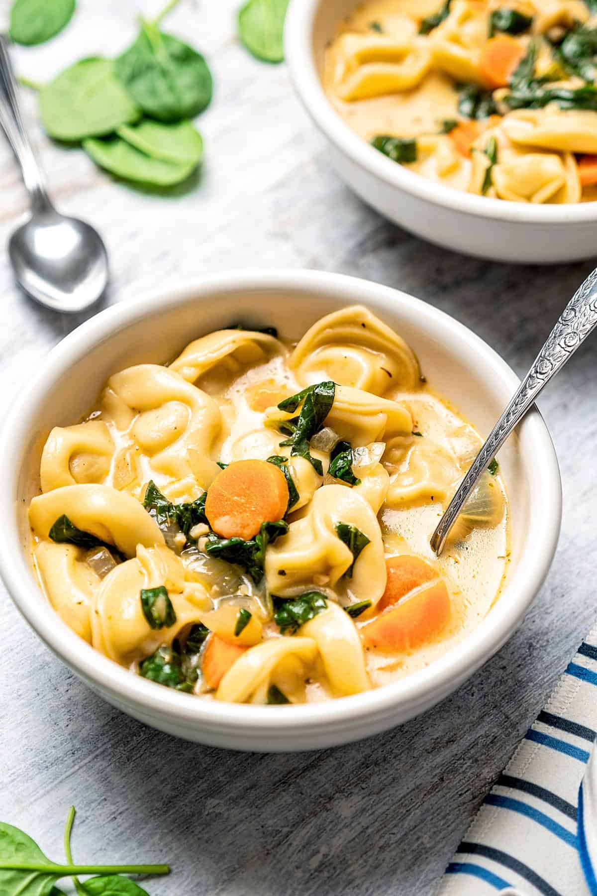 This creamy Tortellini Soup with spinach is an easy vegetarian soup recipe packed with tender cheese tortellini, fresh veggies, and lots of flavor! Two bowls filled with a creamy tortellini soup.