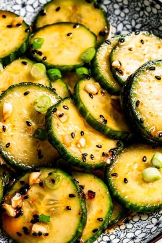 Close-up of Asian cucumber salad garnished with black sesame seeds and green onions.