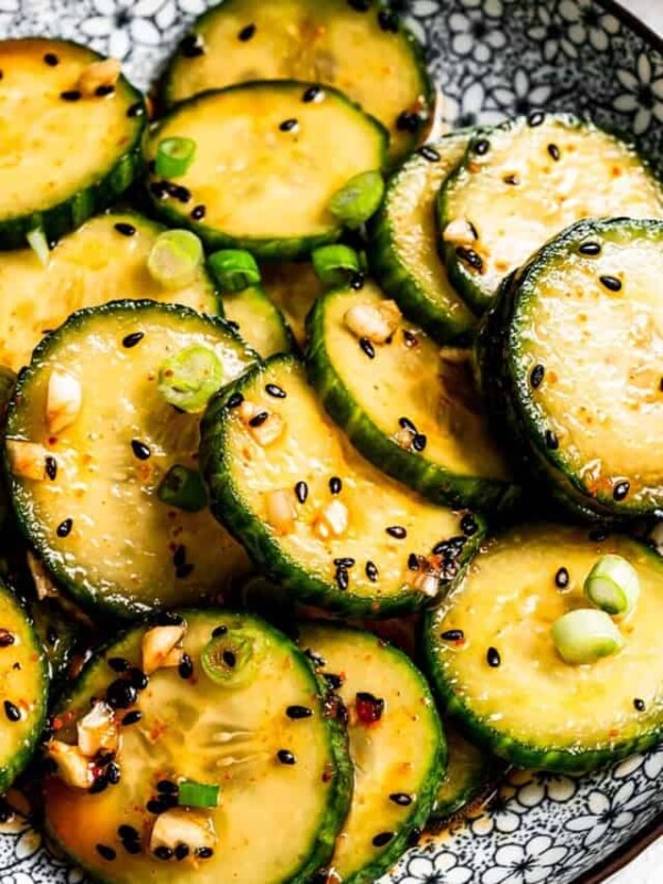 Close-up of Asian cucumber salad garnished with black sesame seeds and green onions.