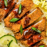 Pork Katsu cutlet served with katsu sauce, cucumber, rice, and salad.