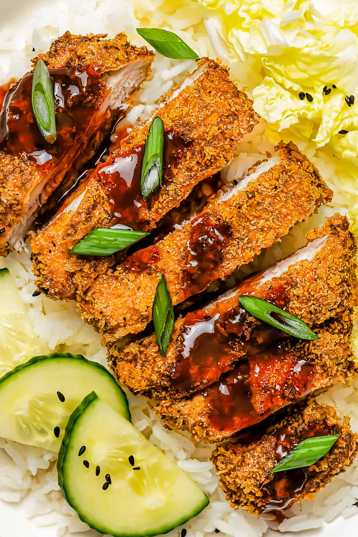 Pork Katsu cutlet served with katsu sauce, cucumber, rice, and salad.