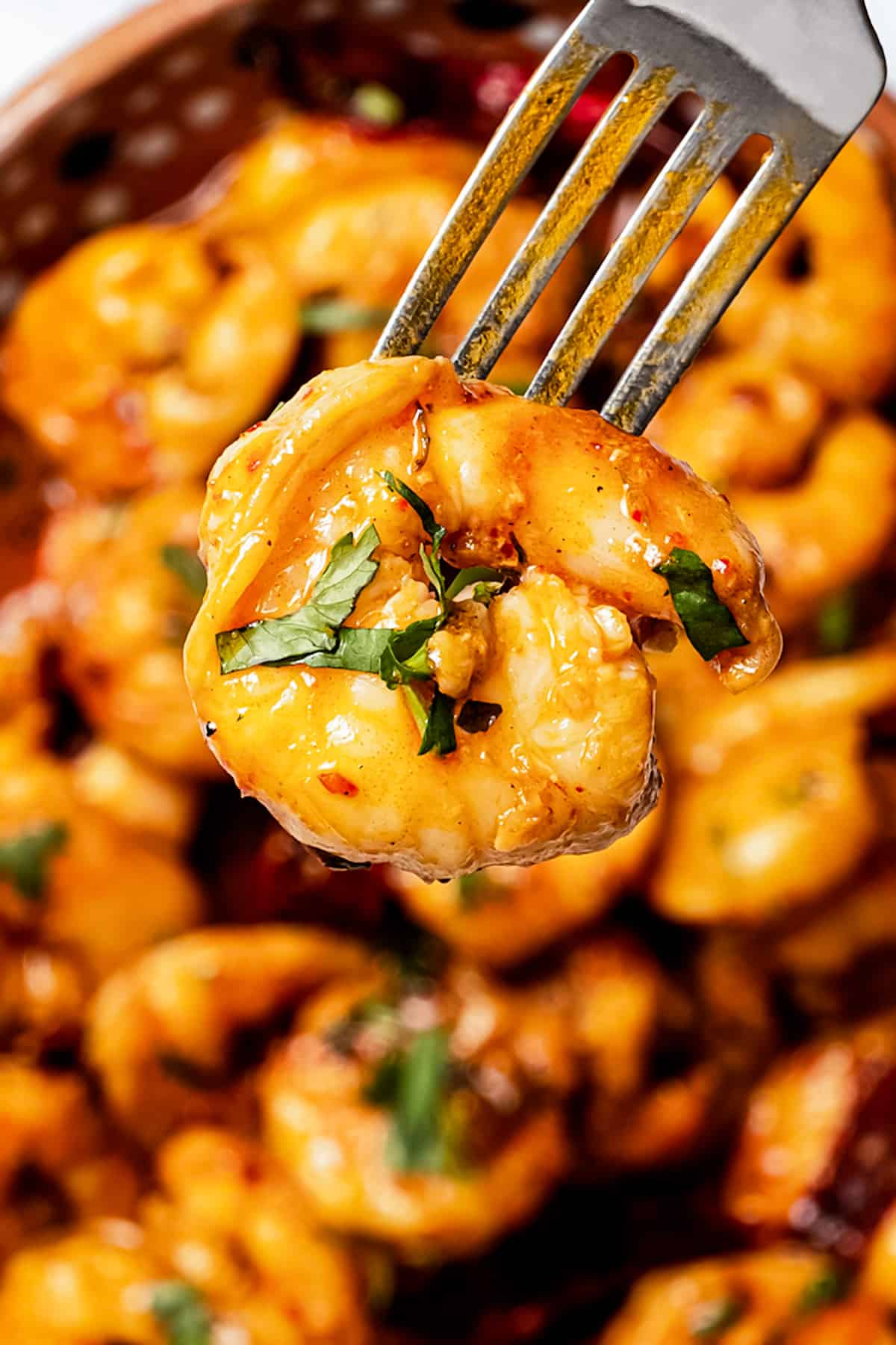 Close-up of a garlic butter shrimp on a fork.
