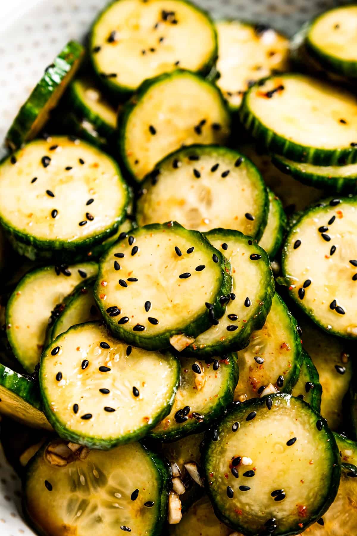 Close-up of Asian cucumber salad garnished with black sesame seeds.