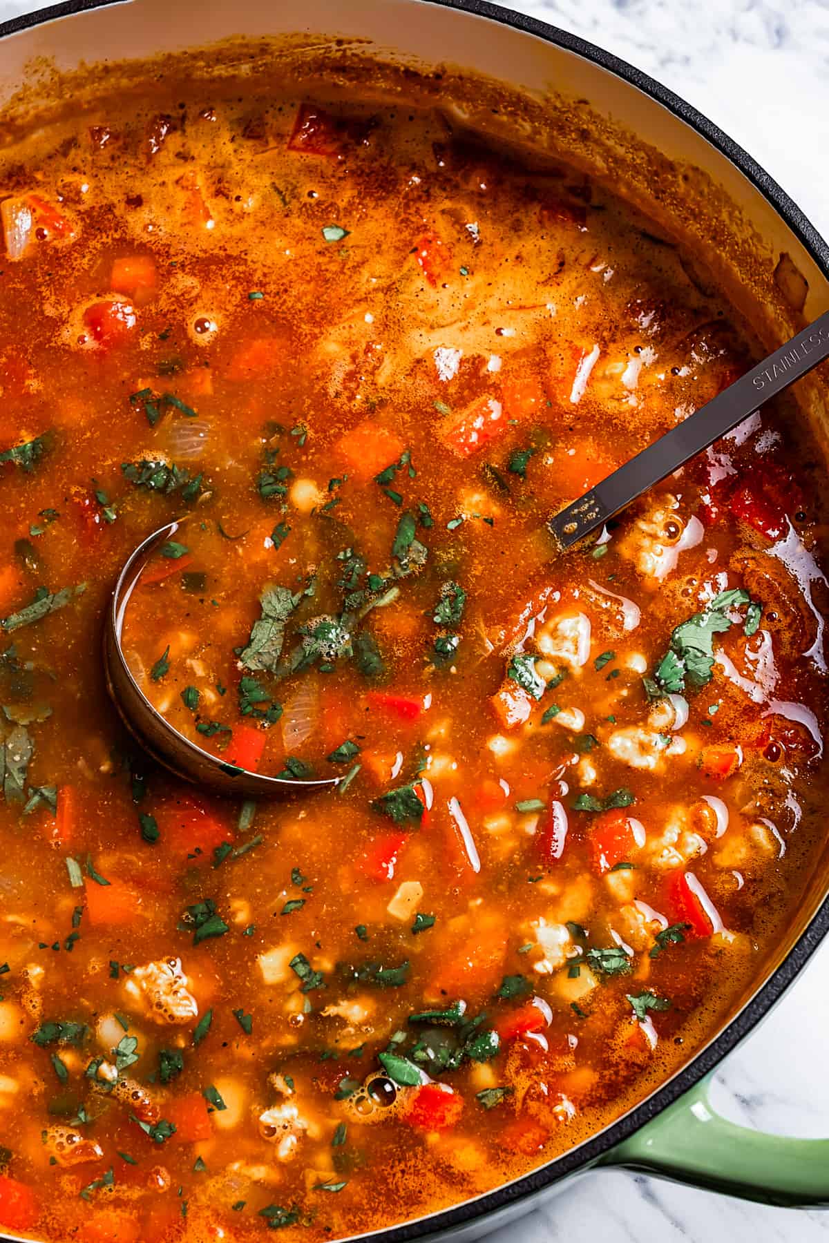 Brothy taco soup in a pot with a ladle placed inside the soup.