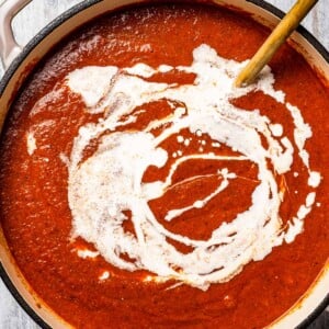 Adding the heavy cream-cornstarch slurry to a tomato soup.