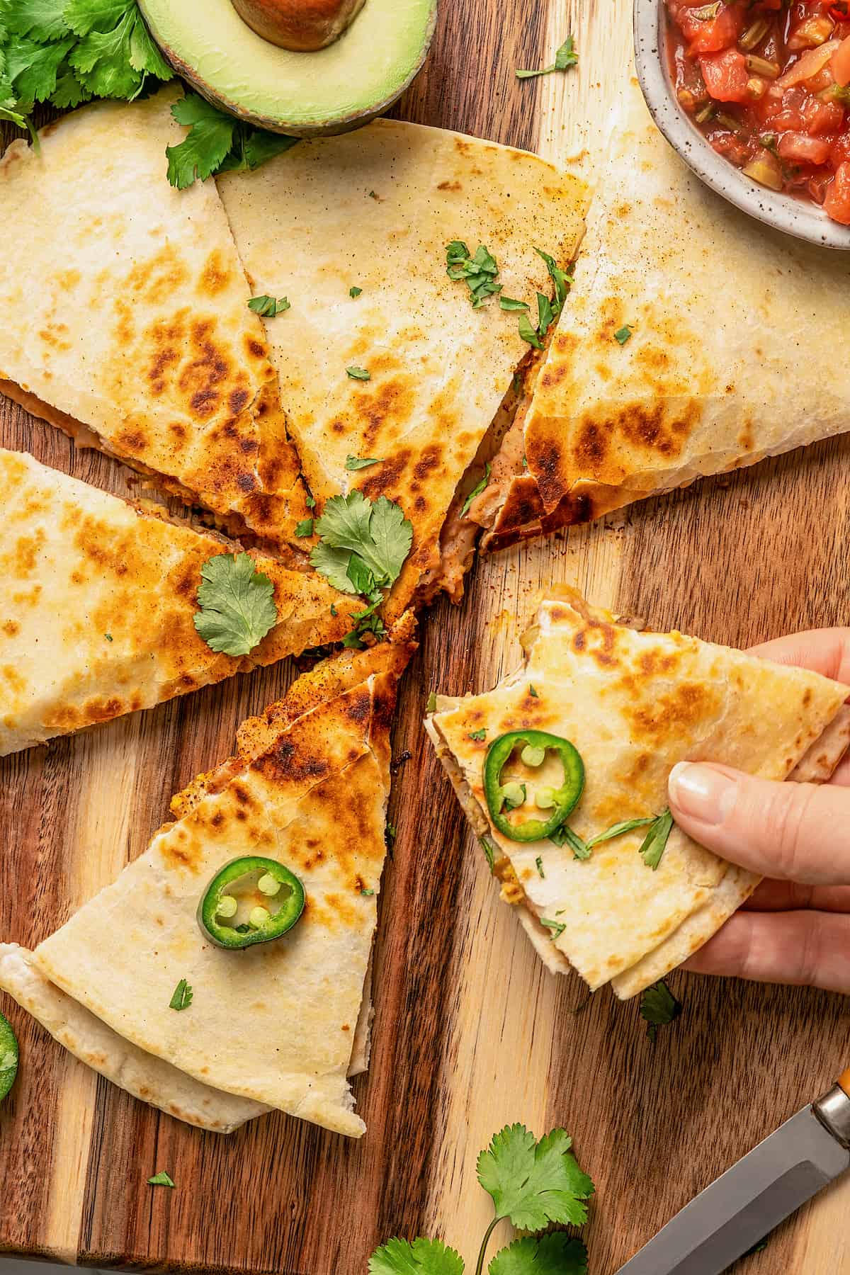 Perfectly crunchy, cheesy breakfast quesadillas stuffed with breakfast favorites like scrambled eggs, refried beans, bacon, and potatoes. Pulling apart a slice of easy breakfast quesadillas.