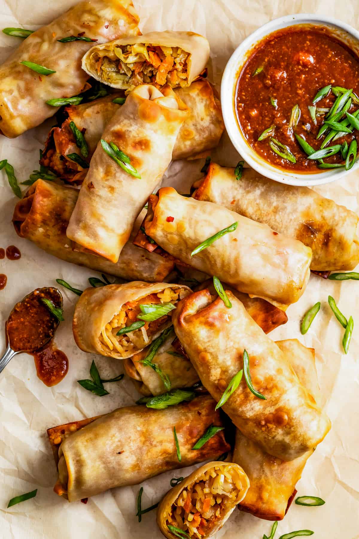 overhead shot of Air fryer spring rolls with peanut sauce served on a flat surface.