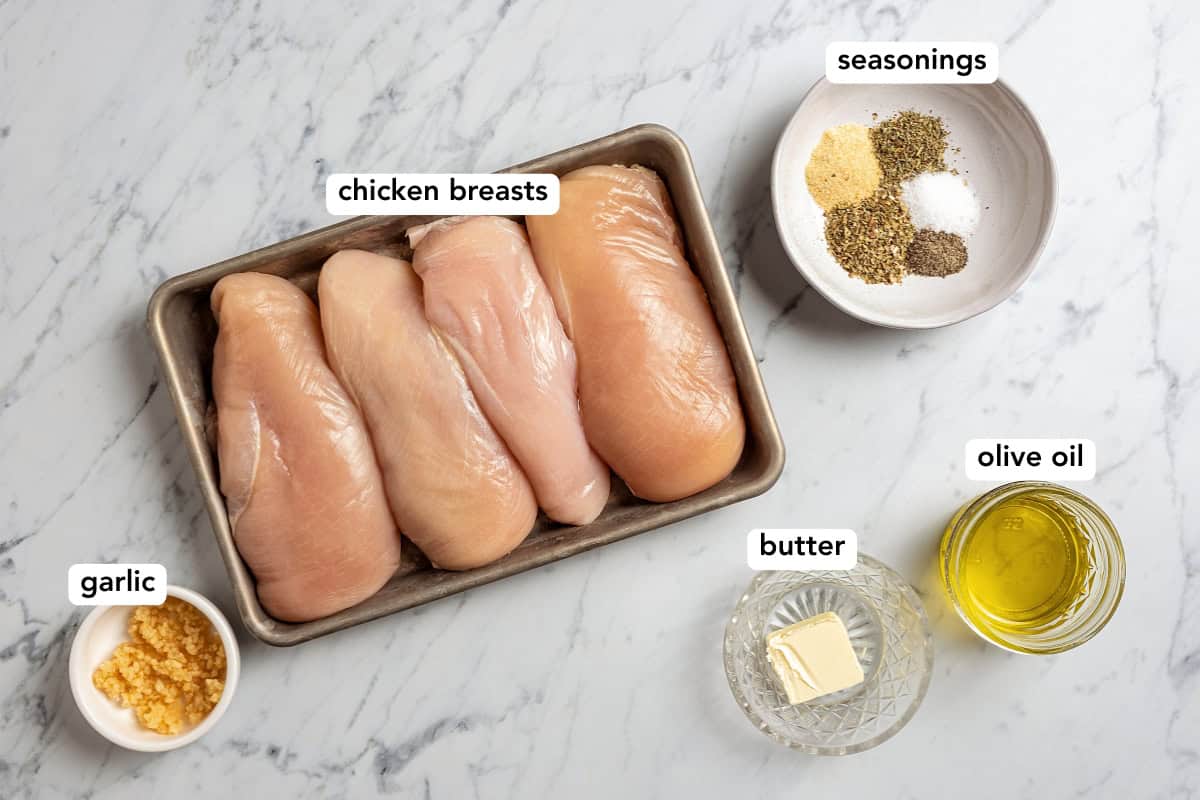 Ingredients for baked chicken breast arranged on a light surface.