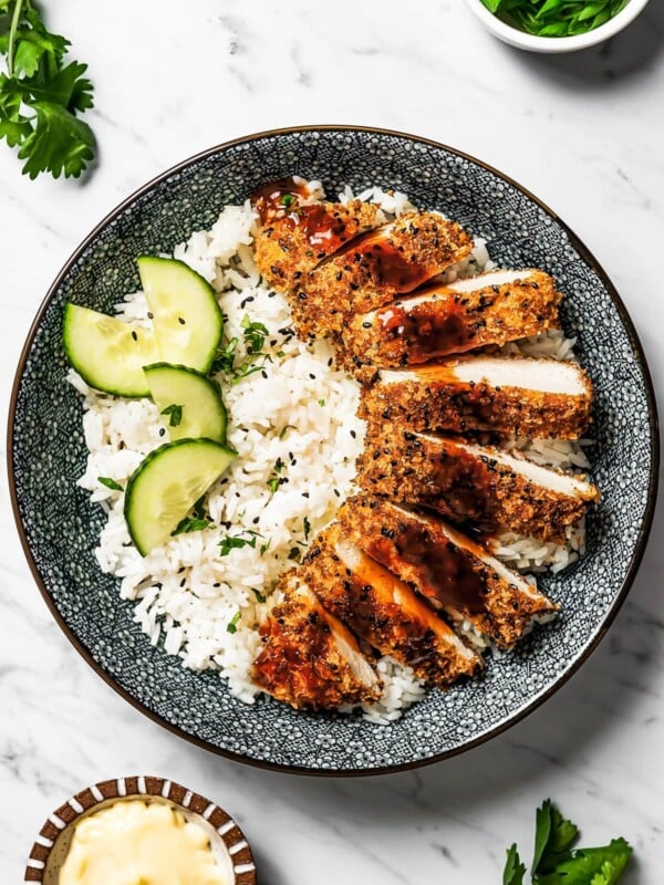 Chicken Katsu served over rice with a cucumber salad on the side.