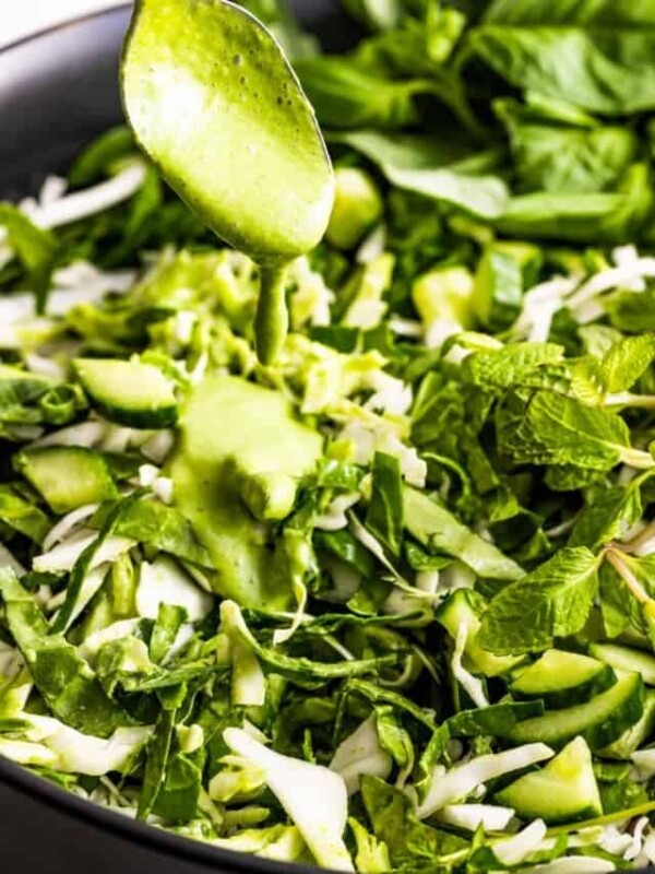 Adding green dressing to a salad.