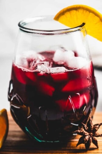 Close-up of glass of Jamaican sorrel with an orange wedge.